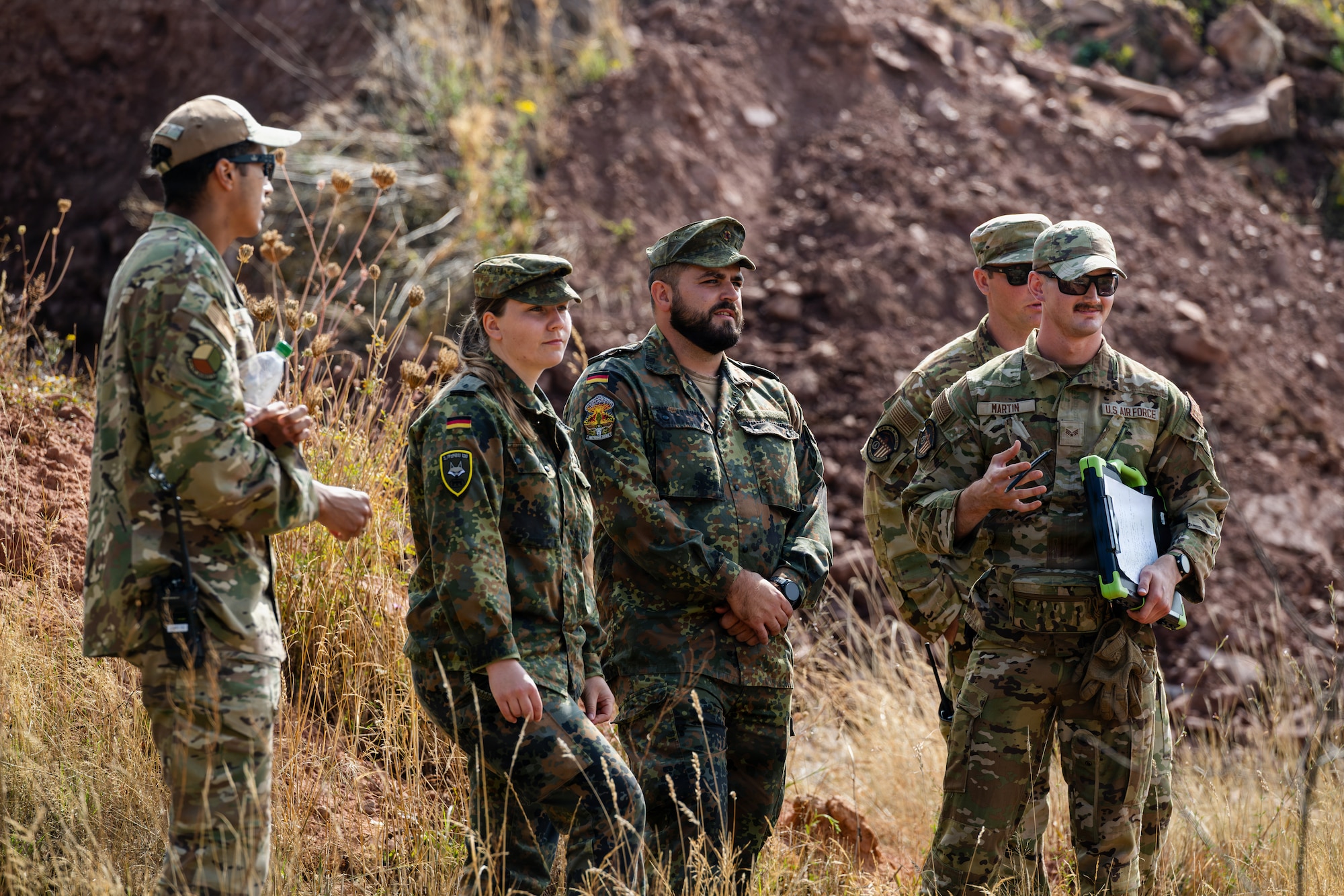 Military members stand in a field.