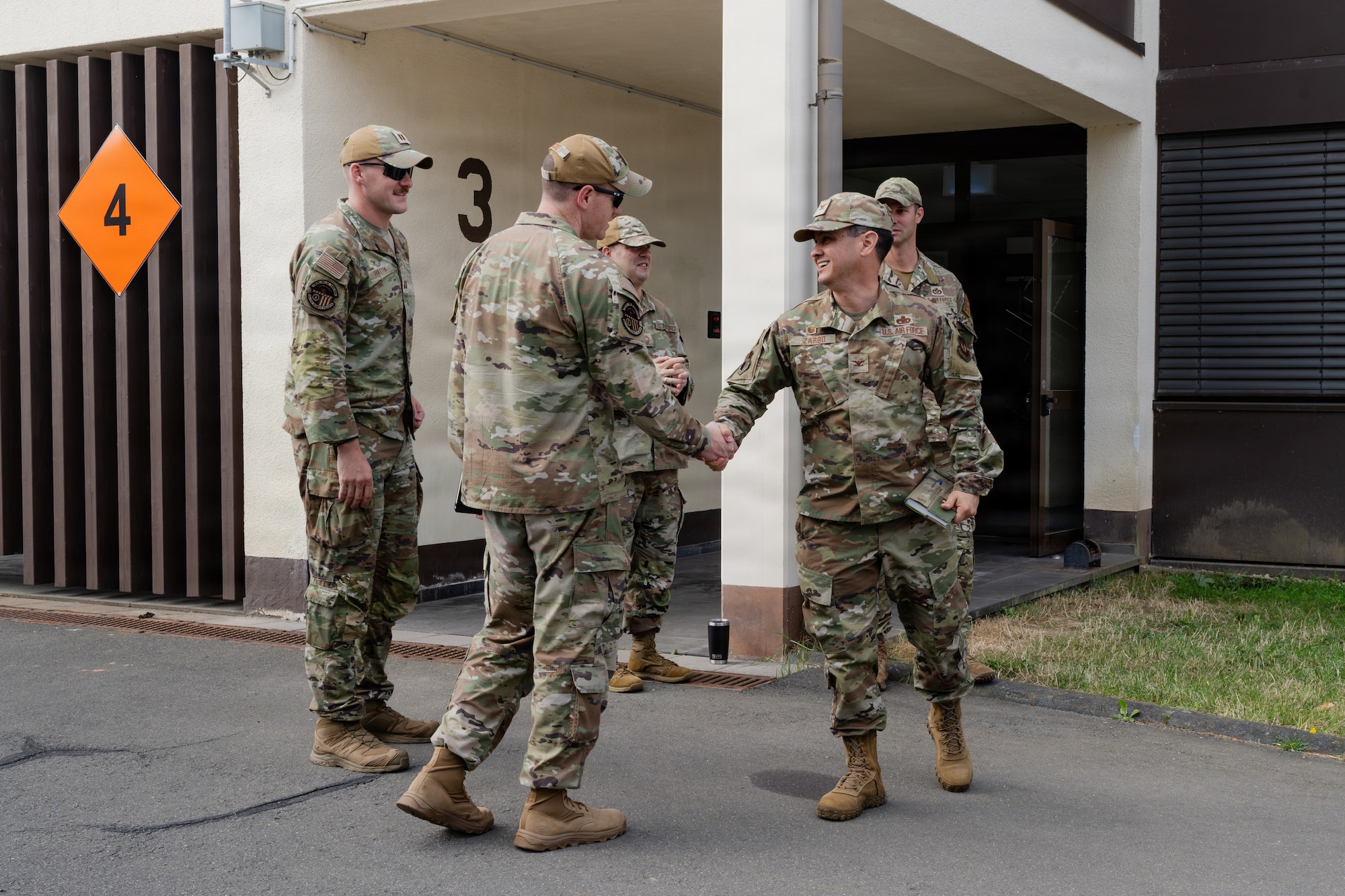 U.S. Air Force Airmen shake hands outside of a building.