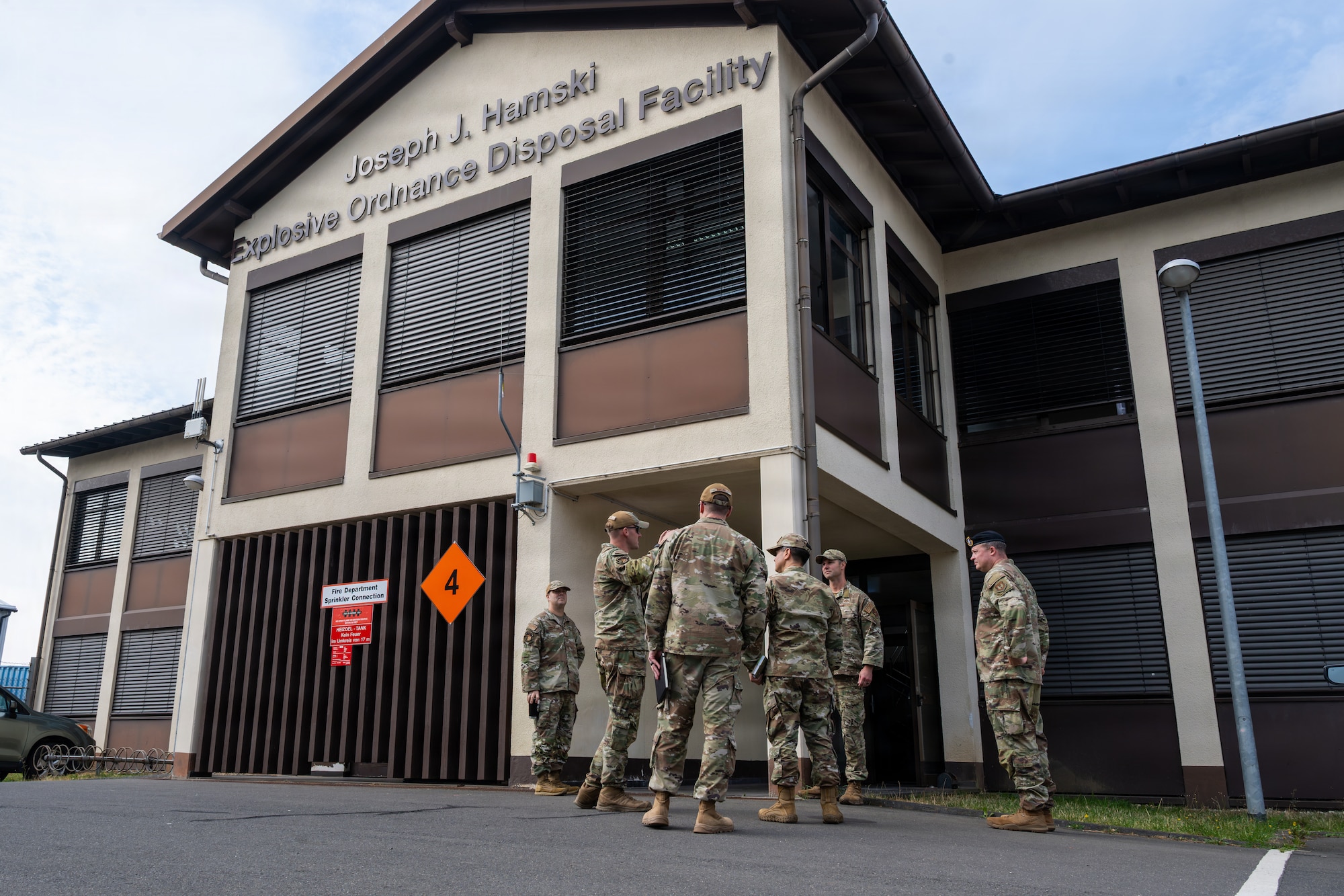 U.S. Air Force Airmen stand in front of a building.