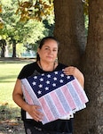 Sandra Nunez-Lopez, a medical support assistant at Kenner Army Health Clinic, holds a folded Flag of Honor close to her heart.