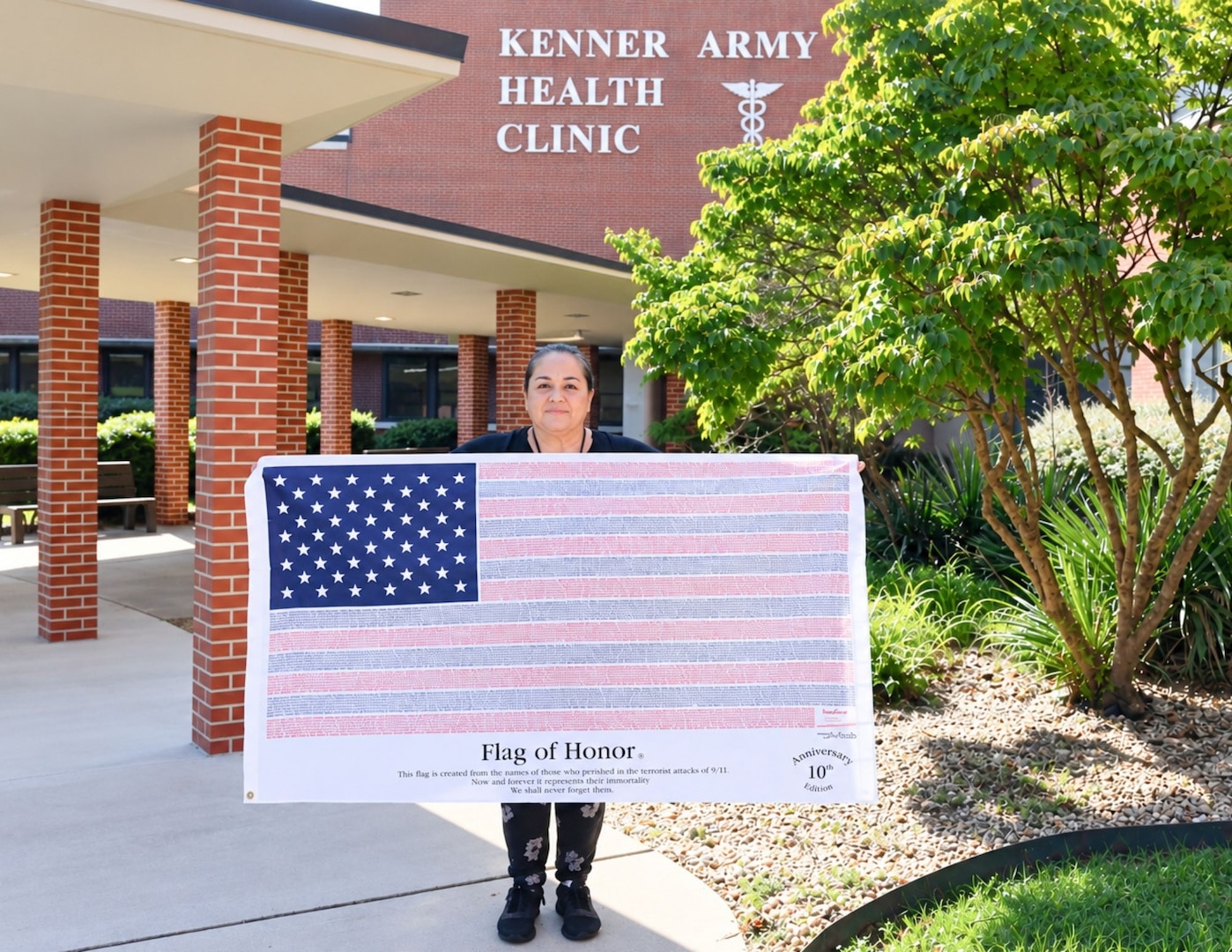 Sandra Nunez-Lopez, a medical support assistant at Kenner Army Health Clinic, holds a Flag of Honor outside of Kenner Army Health Clinic