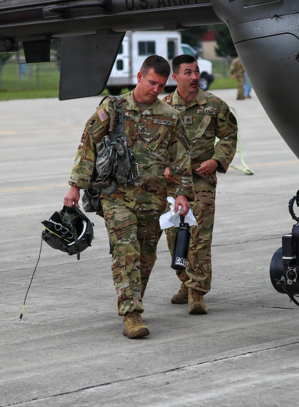 U.S. Army Sgt. 1st Class Shawn Firkins and Staff Sgt. Christopher Poole, crew chiefs with Charlie Company, 1st Battalion, 376th Aviation Regiment, Kentucky National Guard, head out to the aircraft prior to their simulated surveillance mission at Volk Field Combat Readiness Training Center (CRTC), Wisconsin, during Patriot 26, Aug. 25, 2026.