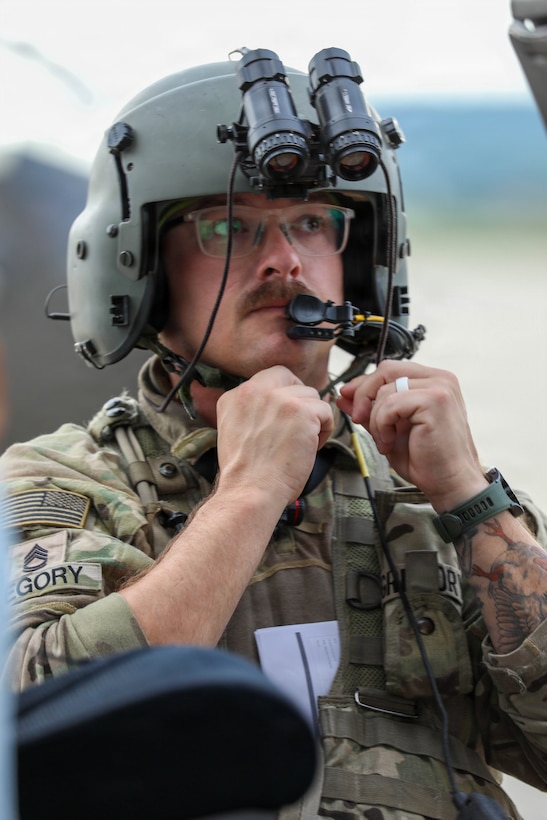 U.S. Army Sgt. 1st Class Devon Gregory, a crew chief with Charlie Company, 1st Battalion, 376th Aviation Regiment, Kentucky National Guard, dons his flight gear before conducting a simulated surveillance mission at Volk Field Combat Readiness Training Center, Wisconsin, during Patriot 26, Aug. 25, 2026.