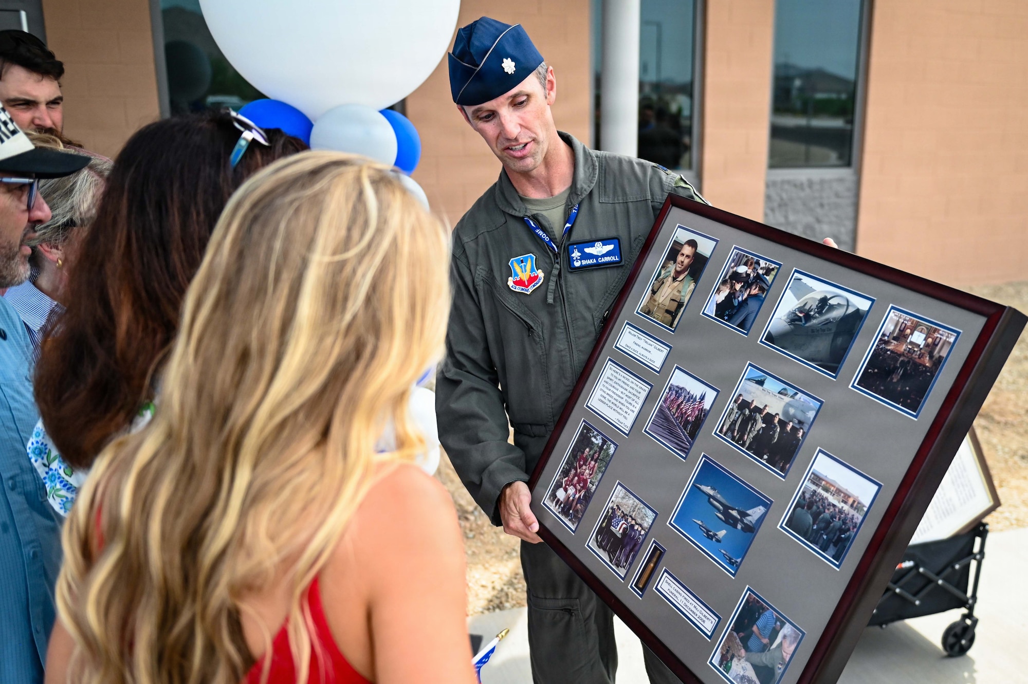 U.S. Air Force Lt. Col. Shayne Carroll, 309th Fighter Squadron commander, shows a commemorative photo box to the family of Maj. Troy L. Gilbert during the Troy Gilbert Elementary School ribbon-cutting ceremony in Waddell, Arizona, Aug. 28, 2026. The presentation celebrated Gilbert's sacrifice and highlighted the unbreakable bond between Luke Air Force Base and the local community that continues to honor his service. (U.S. Air Force photo by Senior Airman Albert Morel)