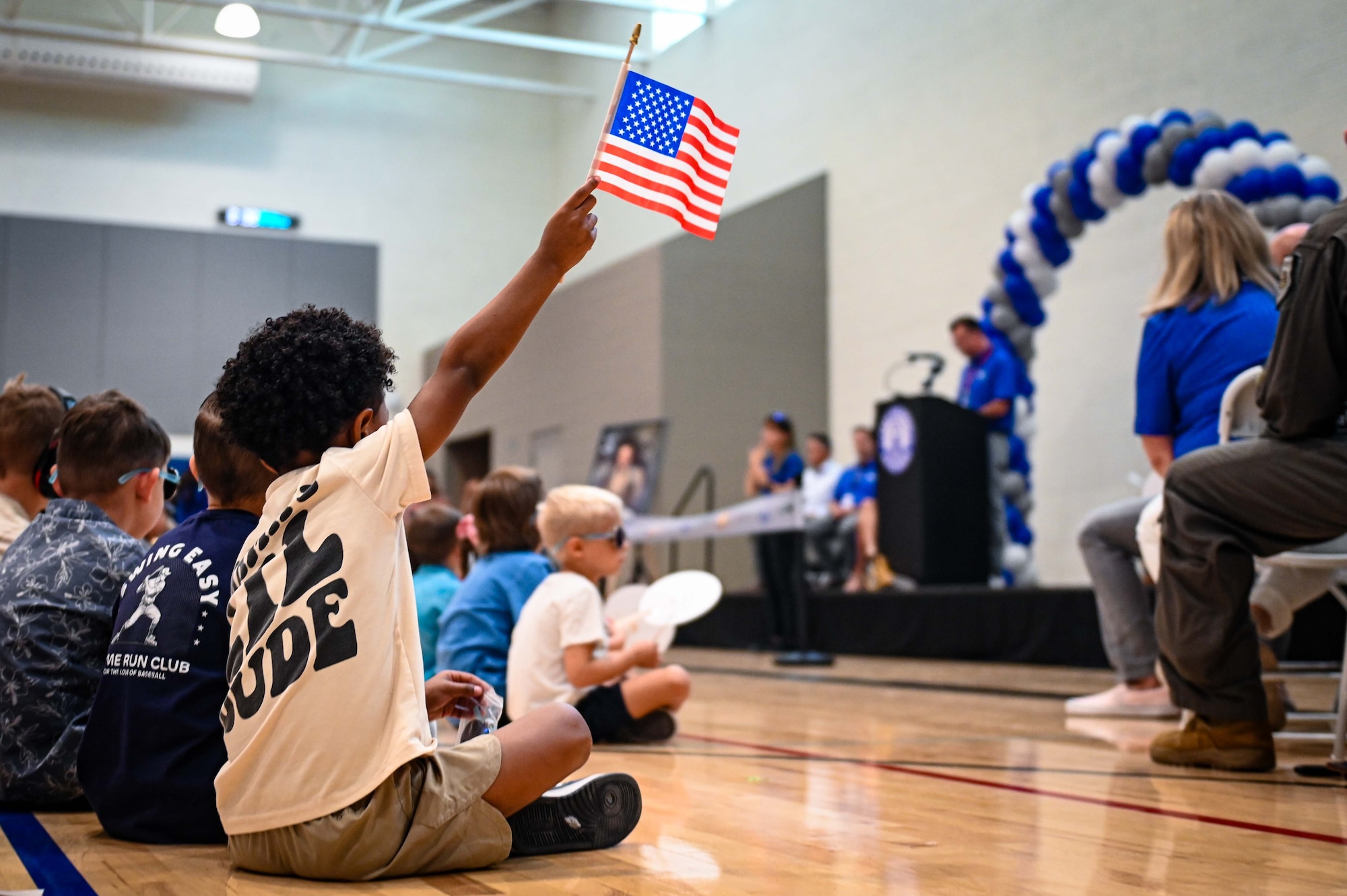 A student waves an American flag during the Troy Gilbert Elementary School ribbon-cutting ceremony in Waddell, Arizona, Aug. 28, 2026. Troy Gilbert Elementary School was named in honor of U.S. Air Force Maj. Troy L. Gilbert, a former F-16 Fighting Falcon pilot previously assigned to Luke Air Force Base's 309th Fighter Squadron. (U.S. Air Force photo by Senior Airman Albert Morel)