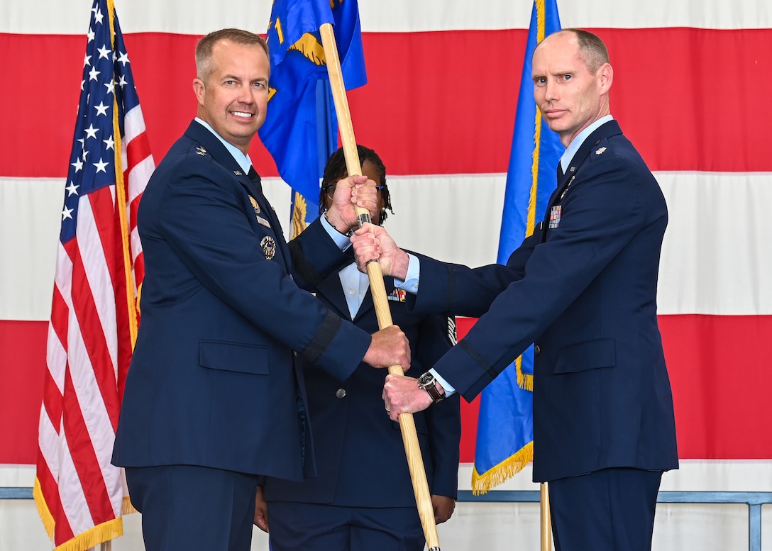 Maj. Gen. Ty Neuman, left, Eighth Air Force and Joint-Global Strike Operations Center commander, and Lt. Col. Joshua Dawkins, B-21 Integration Detachment 1 commander, exchange the unit’s guidon