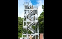 A photo of members of Joint Base Lindsey Graham climbing a tower outdoors.