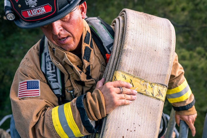 A photo of a fire fighter wearing full gear, walking up a tower.