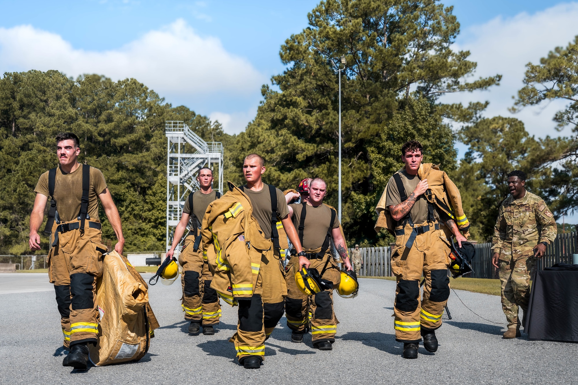 A photo of a group of fire fighters walking away from a tower.