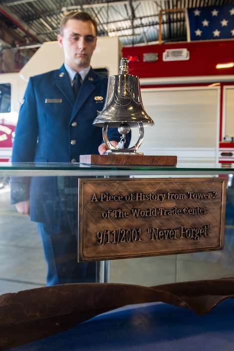 Airman rings a ceremonial bell above a World Trade Center artifact