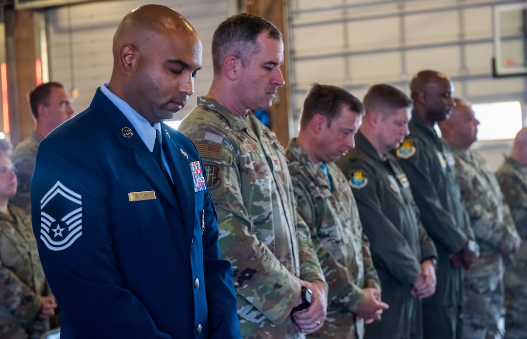 Airmen bow their heads together during an invocation