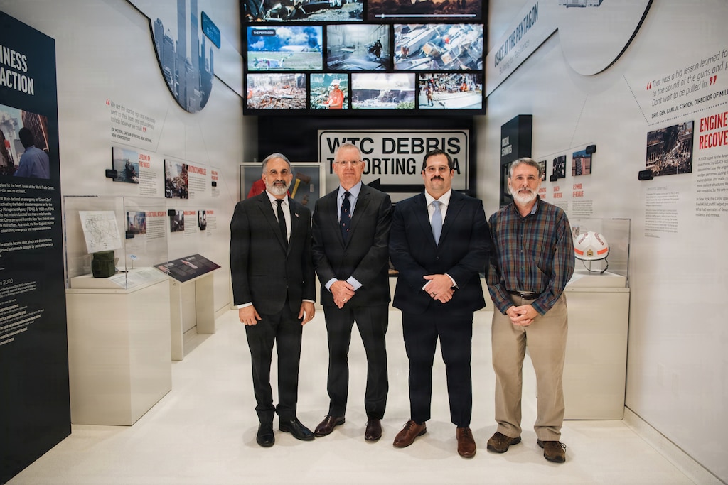 four men stand in front of an exhibit that displays artifacts from the 9/11 terrorist attacks on the World Trade Center in New York City and the Pentagon.