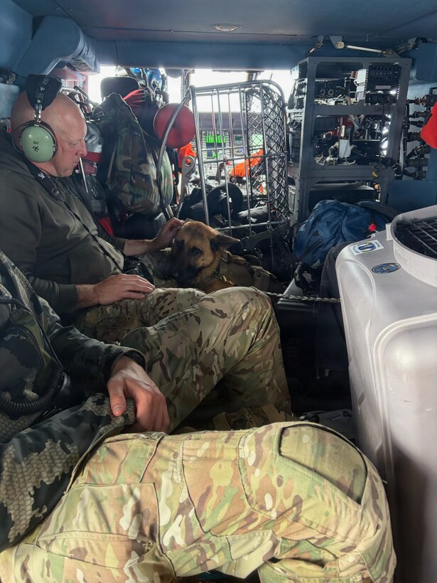 Michigan State Police K-9 Unit officers and their dog sit aboard a U.S. Coast Guard Air Station Traverse City MH-60 Jayhawk helicopter as they transit Lake Superior en route to Isle Royale, Michigan, September 12, 2026. Michigan State Police were transported to the island via Coast Guard helicopter to search for a man who had been missing for days. (U.S. Coast Guard Courtesy photo by Air Station Traverse City)
