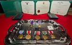 (From center-left) A Purple Heart, Silver Star, American Campaign Medal, WWII Victory Medal, WWII Occupation Medal with "Germany" clasp, European/African/and Middle Eastern Campaign Medal with four bronze stars, and a Good Conduct Medal, lie on a table before World War II veteran Arthur W. Owens is awarded the Silver Star and Purple Heart 68 years after his heroic actions while fighting near Ludwigshafen, Germany. On March 23, 1945, Owens' tank was hit by a shell from an anti-tank gun.  After evacuating the vehicle, he returned twice under heavy enemy fire -- and despite his wounds -- to rescue injured comrades. After a review of his records, Secretary of the Army John McHugh recently signed orders to recognize Owens. Brig. Gen. Mike Bridges, commander of the Alaska Army National Guard, presented the medals during a ceremony at the Alaska National Guard headquarters on Joint Base Elmendorf-Richardson, Alaska, Thursday, Sept. 19, 2013. (U.S. Air Force photo by Justin Connaher/Released)
