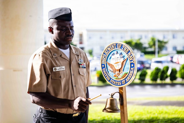 Hospital Corpsman 1st Class Amos Asare, a chief petty officer selectee assigned to Navy Medicine Readiness and Training Command (NMRTC) Okinawa, rings a ceremonial bell during a moment of silence at a morning colors ceremony on Camp Foster, Okinawa, Japan, Sept. 11, 2026. The ceremony, coordinated by the command’s chief selectees, commemorated the 25th anniversary of the 9/11 attacks. (U.S. Navy photo by Mass Communication Specialist 1st Class Simon Pike)