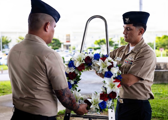 Hospital Corpsman 1st Class Chris Hobbs, right, and Hospital Corpsman 1st Class Rhyan Capili, both assigned to Navy Medicine Readiness and Training Command (NMRTC) Okinawa, present a wreath during a morning colors ceremony on Camp Foster, Okinawa, Japan, Sept. 11, 2026. The ceremony, coordinated by the command's chief petty officer selectees, commemorated the 25th anniversary of the 9/11 attacks. (U.S. Navy photo by Mass Communication Specialist 1st Class Simon Pike)