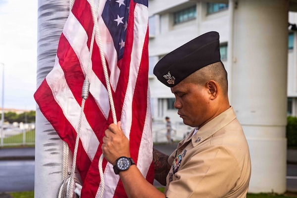 Hospital Corpsman 1st Class Rhyan Capili, a chief petty officer selectee assigned to Navy Medicine Readiness and Training Command (NMRTC) Okinawa, hoists the American flag during a morning colors ceremony on Camp Foster, Okinawa, Japan, Sept. 11, 2026. The ceremony, coordinated by the command’s chief selectees, commemorated the 25th anniversary of the 9/11 attacks. (U.S. Navy photo by Mass Communication Specialist 1st Class Simon Pike)