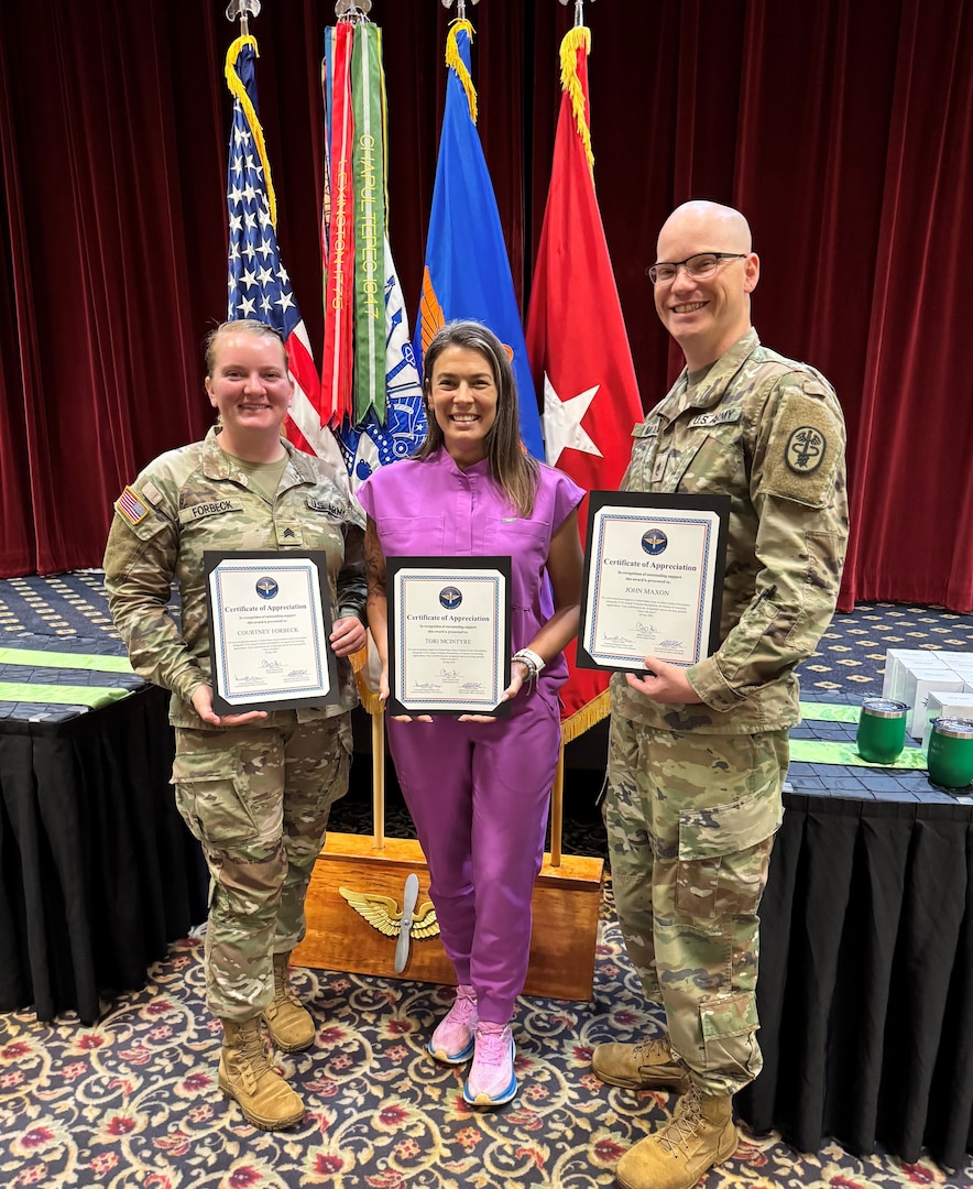 Staff Sgt. Courtney Forbeck, Tori McIntyre, RN, and Staff Sgt. John Maxon, stand together after receiving Certificates of Appreciation during the Volunteer Appreciation Ceremony at Fort Rucker, Alabama, May 28, 2026. The three Lyster Army Health Clinic staff members were recognized for their outstanding off-duty dedication, community service, and commitment to caring for those around them.