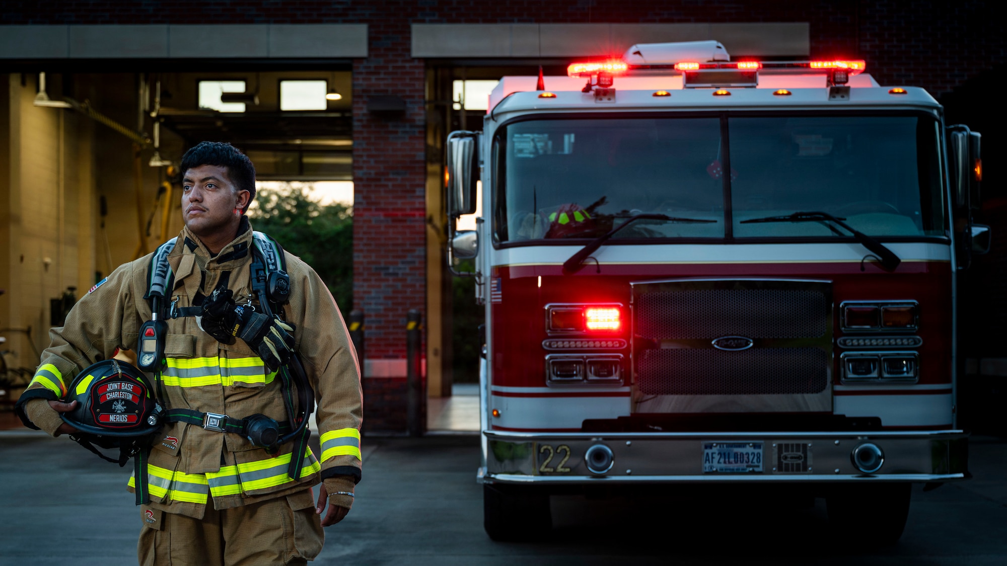 A man in firefighter gear stands in front of a fire truck.