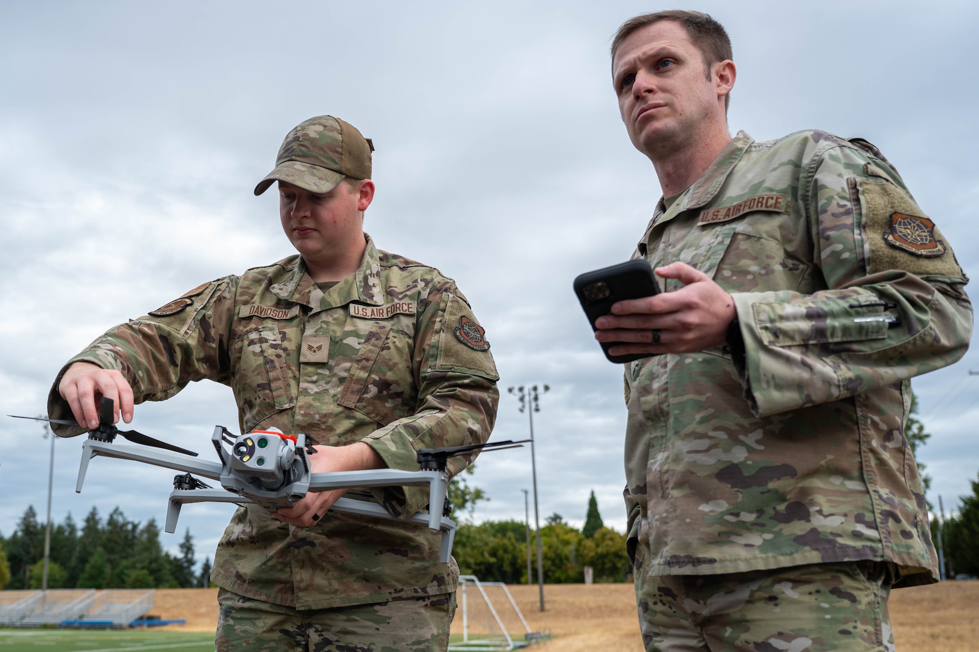 A man manipulates a drone while another stands to the side.