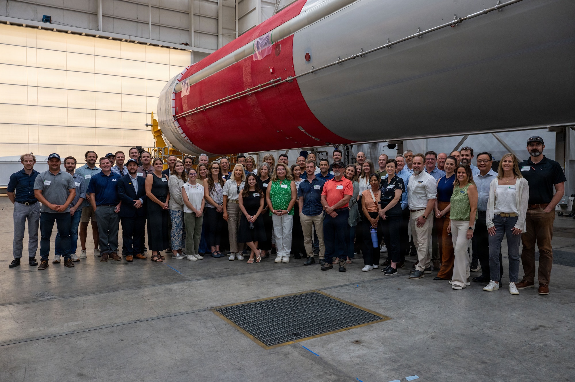 a group of people gather for a photo in front of a horizontal rocket booster