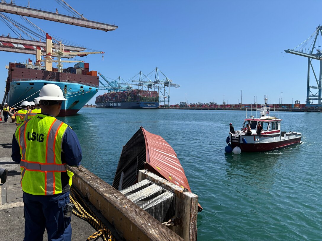 U.S. Coast Guard and Los Angeles Fire Department personnel secure a partially-submerged container to the pier in the Port of Los Angeles, September 14, 2026.