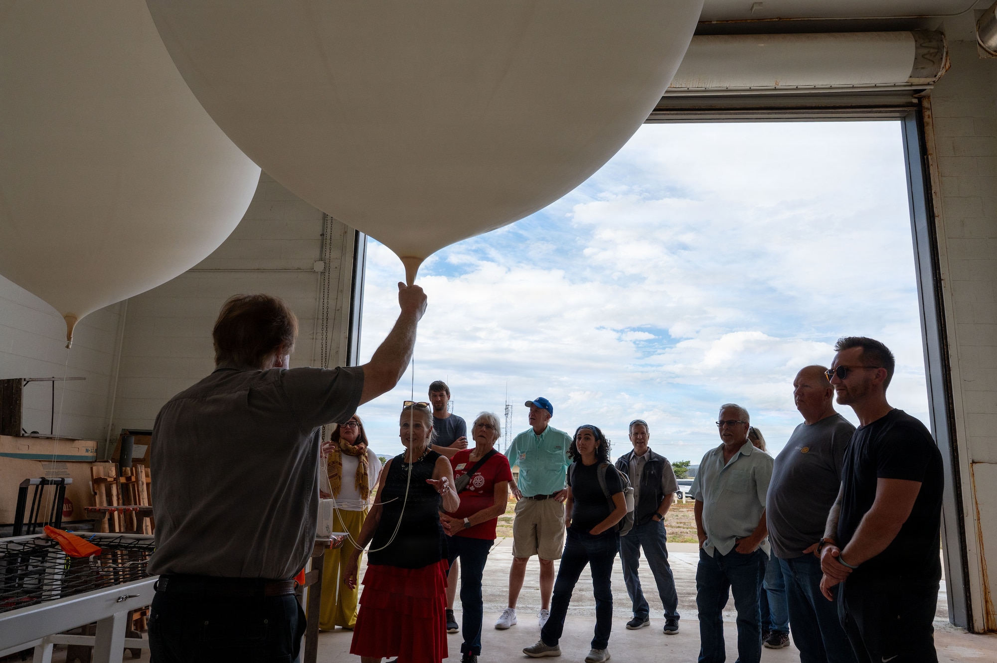 a person speaks to a group of people while holding a weather balloon