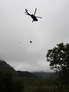 laska Army National Guard Staff Sgt. Steven Gildersleeve, critical care flight medic assigned to G Company, 2nd Battalion, 211th General Support Aviation Battalion, rides the hoist with an injured mountain biker in a litter during a rescue along the Winner Creek Trail near Girdwood, Alaska, Sept. 13, 2026.