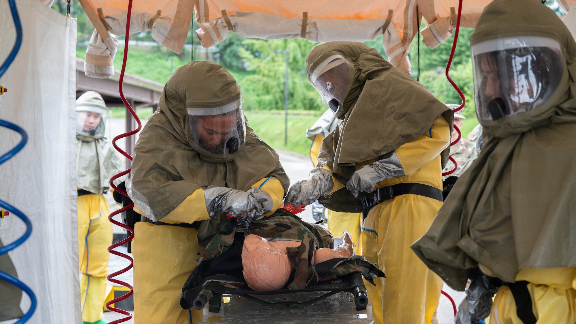 Medical personnel cut clothing away from a training mannequin.