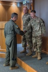 From left, Chairman of the Joint Chiefs of Staff Air Force Gen. Dan Caine, coins  Airman 1st Class Manuel Guzman, 48th Aircraft Maintenance Squadron avionics journeyman, during a visit at RAF Lakenheath, England, Sept. 14, 2026.