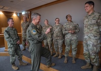 From left, Senior Enlisted Advisor to the Chairman SEAC David Isom, Chairman of the Joint Chiefs of Staff Air Force Gen. Dan Caine, and Tech. Sgt. Jordon Porter, 48th Operations Support Squadron F-15E Strike Eagle aircraft quality assurance office noncommissioned officer in charge, discuss Porter’s accomplishments during a coining ceremony at RAF Lakenheath, England, Sept. 14, 2026.