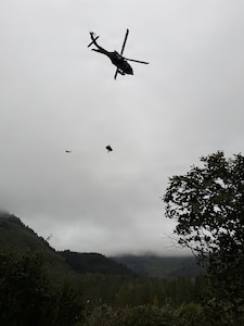 Alaska Army National Guard Staff Sgt. Steven Gildersleeve, critical care flight medic assigned to G Company, 2nd Battalion, 211th General Support Aviation Battalion, rides the hoist with an injured mountain biker in a litter during a rescue along the Winner Creek Trail near Girdwood, Alaska, Sept. 13, 2026.
