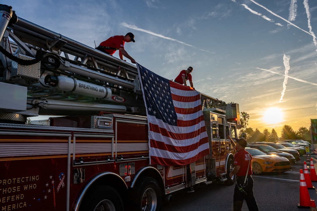 Firefighters hang American flag on the side of fire truck