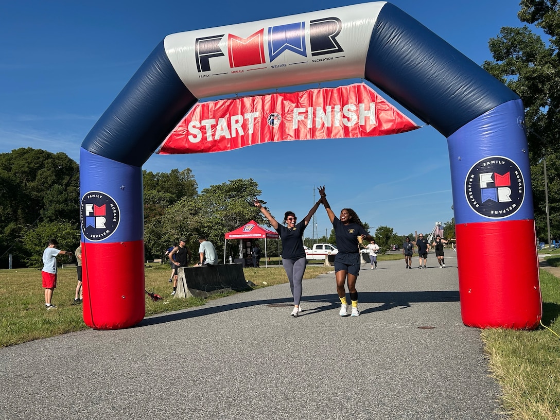 Two women crossing start/finish line holding raised hands