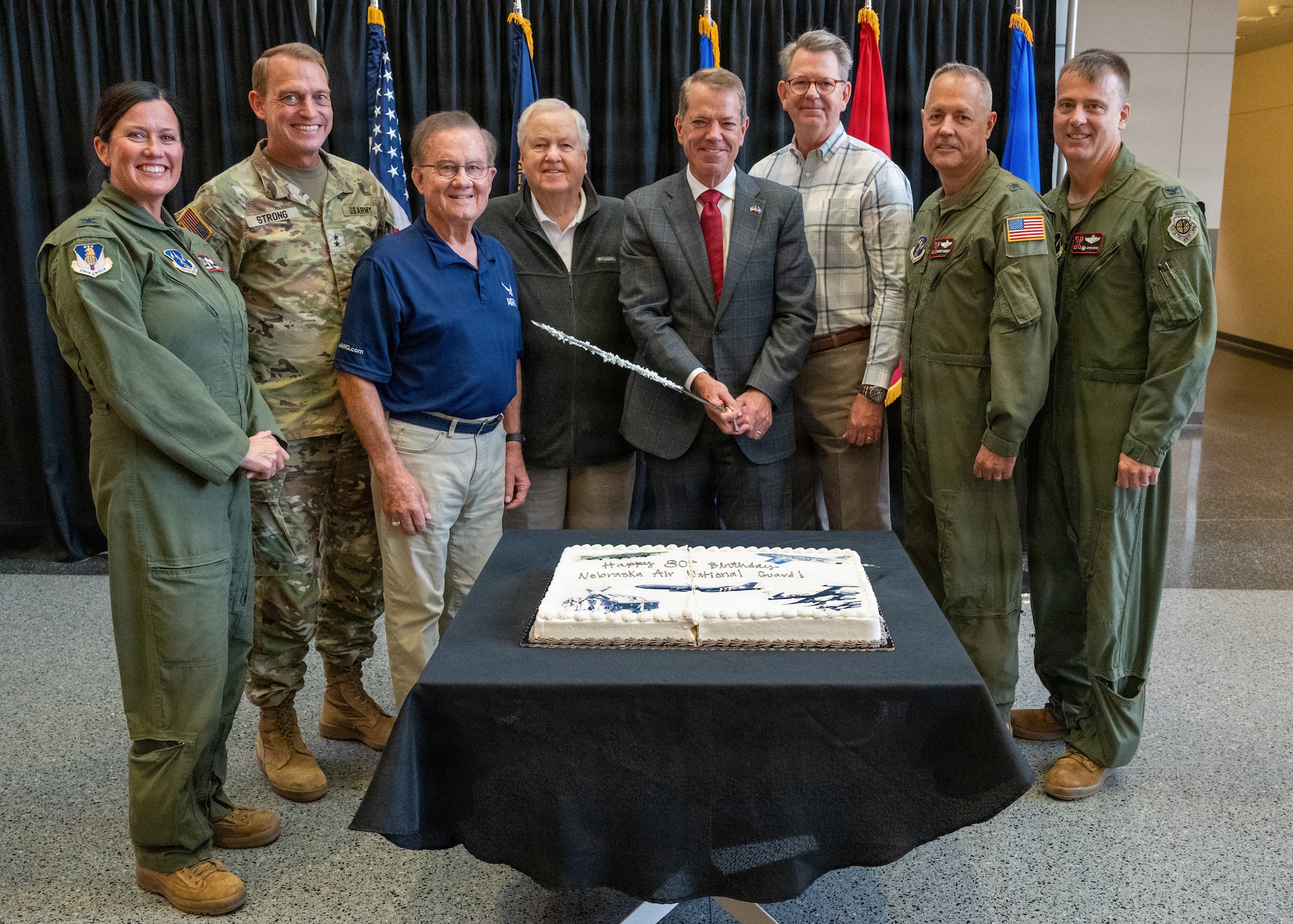 Col. Wendy Squarcia, Maj. Gen. Craig Strong, Maj. Gen (Ret.) Roger Lempke, Brig. Gen. (Ret.) Carl Lorenzen, The Honorable Jim Pillen, Nebraska's governor, Maj. Gen. (Ret.) Bob Stevenson, Brig. Gen. Robert Hargens, and Col. Christopher Hesse gather infront of a birthday cake to commemorate the Nebraska Air National Guard's 80th anniversary at the Nebraska National Guard Joint Force Headquarters in Lincoln, Nebraska, September 13, 2026. The leaders and former leaders of the Nebraska National and Air National Guard gathered to remark on the history and future of the Nebraska Air National Guard. (U.S. Air National Guard photo by Tech. Sgt. Phil Cowen)