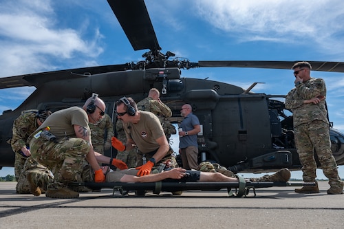 Service members assist patient on stretcher.