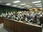 U.S. Army Soldiers and Chilean Army personnel sit and listen to a speaker not in frame.