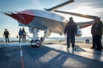 Sailors and Boeing employees look for discrepencies in the positioning of the Boeing unmanned MQ-25 aircraft on the flight deck aboard the aircraft carrier USS George H.W. Bush (CVN 77).  The MQ-25 will be the world’s first operational, carrier-based unmanned aircraft and is integral to the Air Wing of the Future Family of Systems (AWotF FoS). Its initial operating capability (IOC) as an aerial refueling tanker will extend the range, operational capability and power projection of the carrier air wing (CVW) and carrier strike group (CSG). GHWB provides the national command authority flexible, tailorable war fighting capability through the carrier strike group that maintains maritime stability and security in order to ensure access, deter aggression and defend U.S., allied and partner interests. (U.S. Navy photo by Mass Communication Specialist 3rd Class Brandon Roberson)