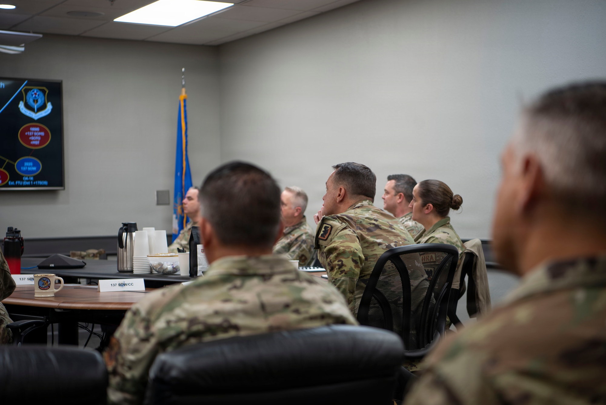 a group of people in uniform sit facing a screen