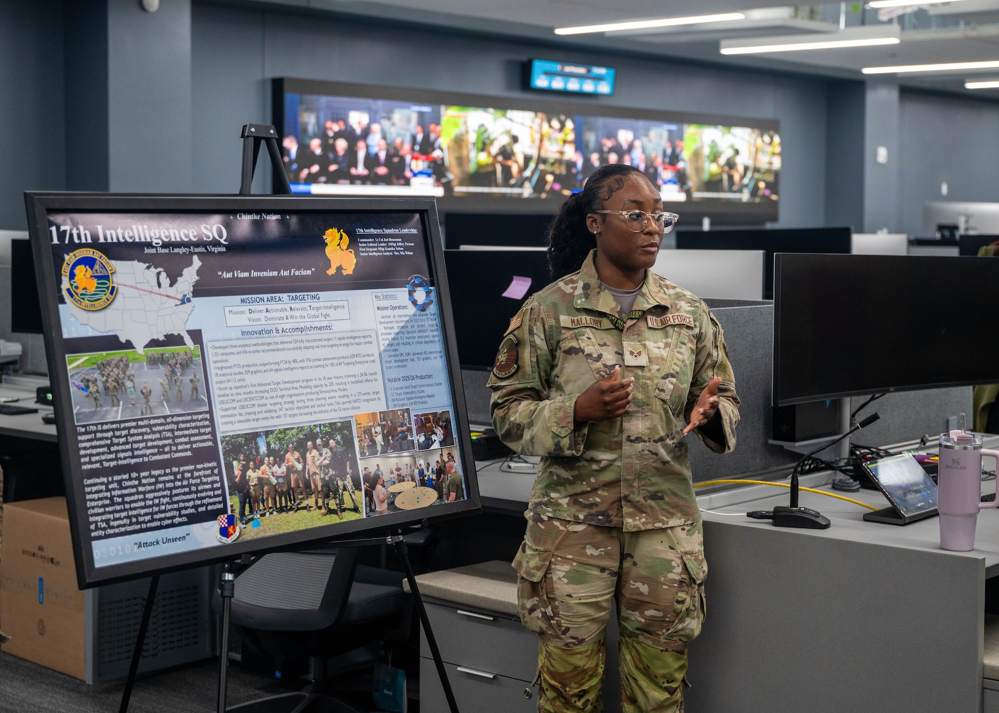 An Airman stands next to a board with stats and information on it.