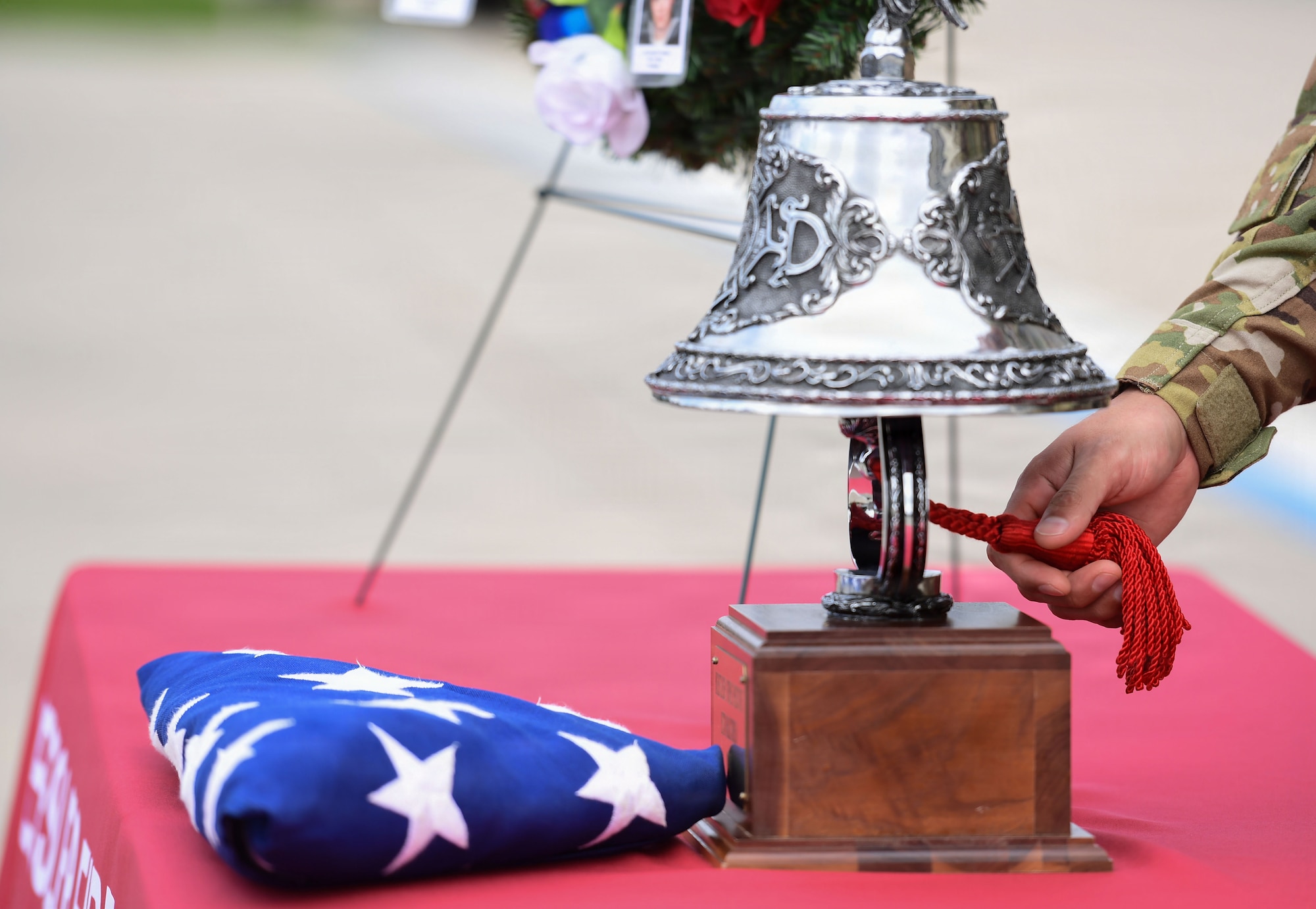 A table displays the U.S. flag and a memory bell which is being rung by a hand.