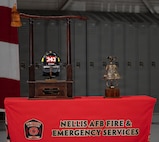 A fire department helmet and ceremonial bell are displayed on top of a table.