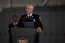 A man is speaking on the podium wearing a formal firemen uniform.